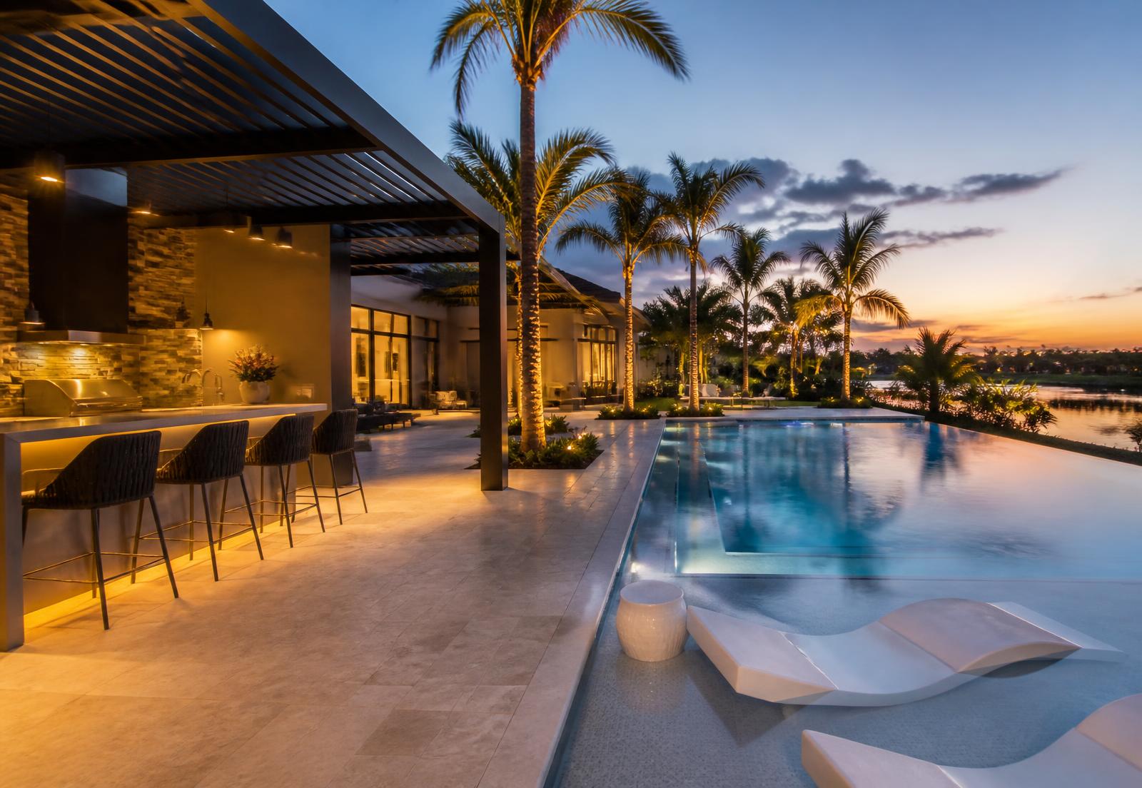 New infinity pool, outdoor kitchen and pergola in a South Florida backyard at dusk
